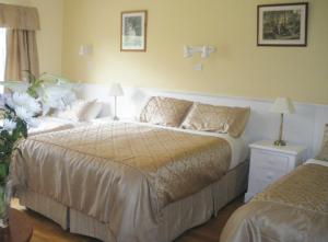 Un dormitorio con una cama grande y una mesa con una lámpara. en Redwood, en Killarney