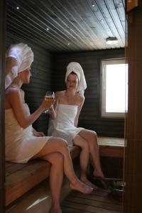 Deux femmes dans un sauna avec un verre de bière dans l'établissement Vuokatin Aateli Ritari & Lady, à Vuokatti