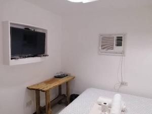 Dieses weiße Zimmer verfügt über einen Tisch und einen TV an der Wand. in der Unterkunft Andreas Homestay in Del Carmen