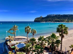 uma vista para uma praia com palmeiras e para o oceano em Poseidon Rooms em Cagliari