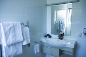 Baño blanco con lavabo y espejo en 850 Cameron Motel en Tauranga