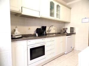 a white kitchen with white cabinets and appliances at Pátio das Cavadas Apartment in Rio Tinto