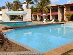 una gran piscina en un complejo con palmeras en Mamelucos Chalé 11 Praia do Flamengo en Salvador