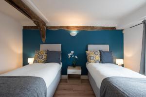 Colchester Town Duplex Apartment في كولشستر: سريرين في غرفة بجدران زرقاء