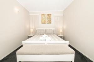 a white bedroom with a white bed with two lamps at Coromandel Apartments in Coromandel Town