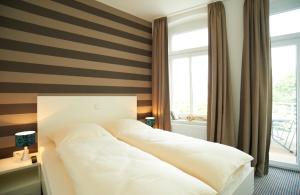 ein Schlafzimmer mit einem weißen Bett und einem Fenster in der Unterkunft Apartment Eisberg 3 mit schöner Balkonterrasse in Norderney