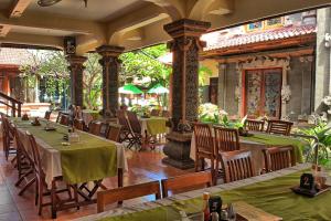 a restaurant with tables and chairs in a building at Masainn Hotel Kuta in Kuta