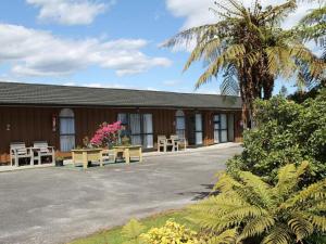 a building with tables and chairs and a palm tree at Buller Bridge Motel in Westport