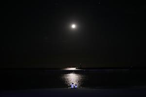 a person in a boat in the water at night at Atelier & Hostel Nagaisa-Ura in Atami