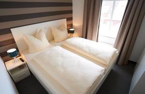 a bedroom with a white bed with a window at Apartment Eisberg 6 mit Balkon in Norderney