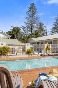 a swimming pool with chairs and a table at Wollongbar Motel in Byron Bay