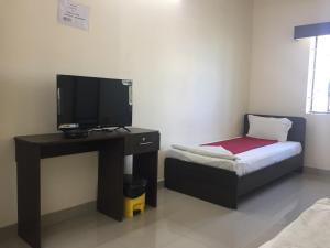 um quarto com uma televisão e uma secretária com uma cama em Sun Shine em Chennai