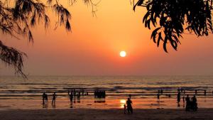 a group of people on the beach at sunset at Hotel Rajendra in Chinchani