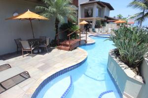 a swimming pool with a table and an umbrella at Hotel Ilhas do Caribe - Na melhor região da Praia da Enseada in Guarujá