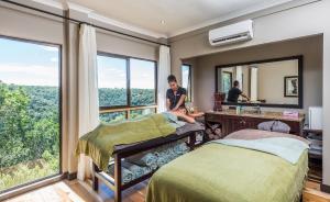 a woman in a room with two beds and a mirror at Kariega Game Reserve Main Lodge in Kenton on Sea
