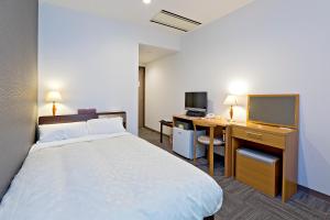 a hotel room with a bed and a desk and a television at Hotel New Ohte in Hakodate