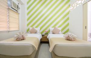 2 camas en una habitación con rayas verdes y blancas en Alicia Tower Residences, en Cebú