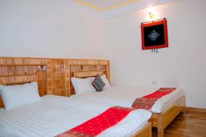 a bedroom with two beds and a picture on the wall at Tạo Phượng Sa Pa Hotel in Sa Pa