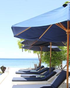 
a beach area with chairs and umbrellas at Seri Resort Gili Meno in Gili Meno
