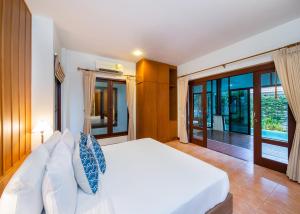 a bedroom with a white bed and sliding glass doors at Blu Marine Hua Hin Resort and Villas - SHA Plus in Hua Hin
