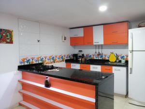 cocina con armarios de color naranja y blanco y nevera en Cabin overlooking the sea and forest, en Tubará