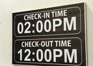 two signs on a wall with a clock in time at Gracious Lodge in Shillong