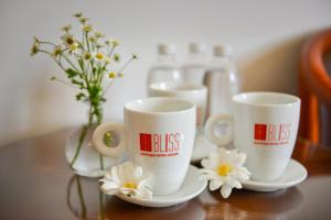 two coffee cups sitting on a table with flowers at Bliss Boutique Saigon - Bùi Viện Walking Street in Ho Chi Minh City