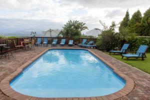 a large blue swimming pool with chairs and tables at Whalesong Hotel & Spa in Plettenberg Bay