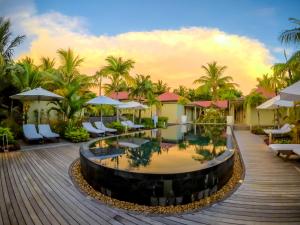 a resort with a pool and chairs and palm trees at Tamassa Bel Ombre in Bel Ombre