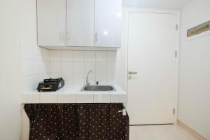 Una cocina con gabinetes blancos y un fregadero. en Minimalist 2BR Apartment The Springlake Summarecon By Travelio, en Bekasi