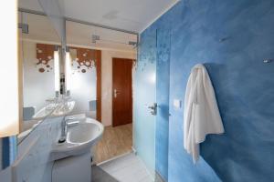 ein blaues Badezimmer mit einem Waschbecken und einem Spiegel in der Unterkunft Victory Gästehaus Therme Erding in Erding