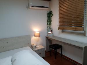 a bedroom with a bed and a desk and a window at Ok guesthouse in Seoul