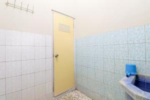 a bathroom with a toilet and a yellow door at Nabhan Homestay in Kalirejo