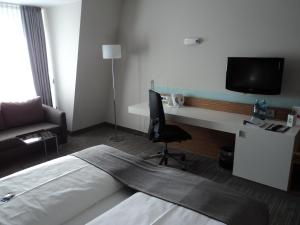 ein Hotelzimmer mit einem Bett und einem Schreibtisch mit einem TV in der Unterkunft Holiday Inn Leipzig Günthersdorf, an IHG Hotel in Kötschlitz