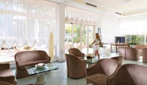 a woman walking in a living room with chairs at Hotel Mocambo in Milano Marittima