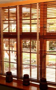 a window with wooden blinds and two stools in front at Sherewood Lodge in Pretoria