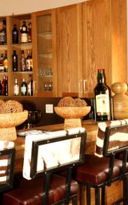 a bar with a counter with stools and bottles of alcohol at Sherewood Lodge in Pretoria