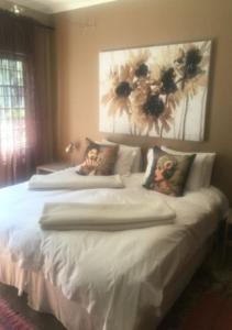 a bedroom with two white beds with flowers on the wall at 278 on Main in Clarens