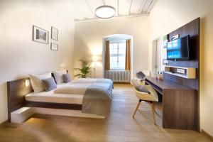 um quarto com uma cama, uma secretária e uma televisão em JUFA Hotel Kronach – Festung Rosenberg em Kronach