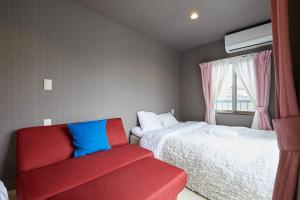 a bedroom with two beds and a red couch at Akabane TK Building 303 in Tokyo