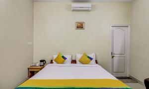 1 dormitorio con 1 cama grande con almohadas amarillas y verdes en Itsy By Treebo - Shree Comforts, en Bangalore