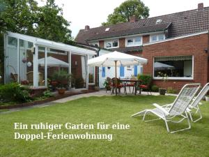 a garden with two lawn chairs and an umbrella at Ferienwohnung Loquard, 15168 in Leer