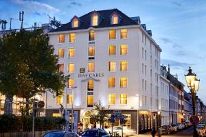 a white building with a sign on it on a street at Das Carls Hotel in Düsseldorf