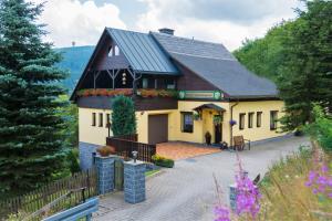 une grande maison jaune avec un toit noir dans l'établissement Pension Am Zechengrund, à Kurort Oberwiesenthal
