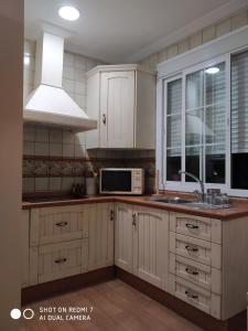 a kitchen with white cabinets and a sink and a microwave at Apartamento Las Musas in Santiponce
