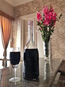 a bottle of wine and a glass on a table with flowers at Apartment Mate in Tbilisi City