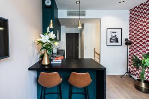 a kitchen with a black island with two chairs at YAYS Paris Issy in Issy-les-Moulineaux