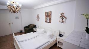 ein weißes Wohnzimmer mit einem Sofa und einem Kronleuchter in der Unterkunft Hotel Seibel in München