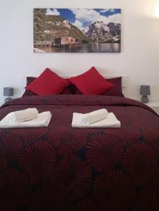 centro monti tiburtini في روما: غرفة نوم بسرير احمر وعليها منشفتين
