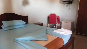 ein Schlafzimmer mit einem Bett und einem roten Stuhl in der Unterkunft DaysInn Hotel in Lira